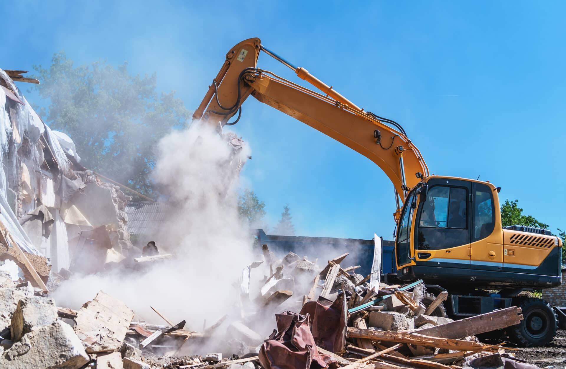Excavator demolishing debris in a construction site, illustrating the process of water damage restoration and debris removal.